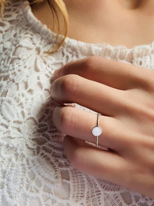 Gros plan main de femme avec la bague Ella représentant un anneau surmonté d'une plaque ronde tout en argent