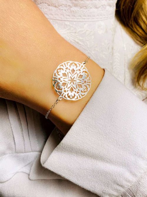 Gros plan poignet de femme avec un bracelet chaîne en argent avec un gros mandala
