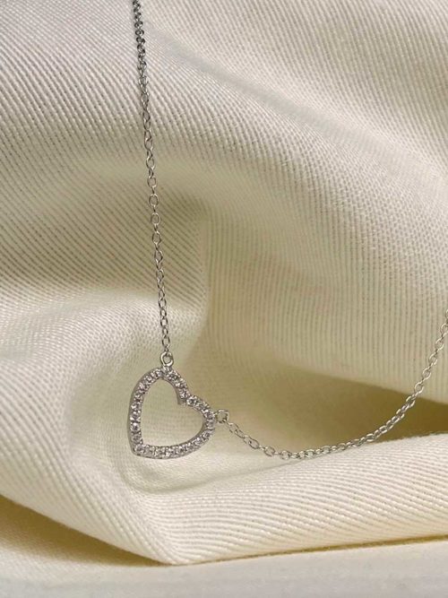 Gros plan sur un tissu blanc le collier Léana en argent avec pendentif en forme de coeur en zircon