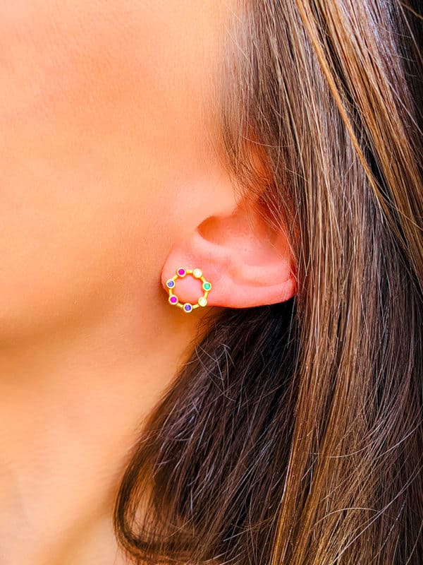 Gros plan visage de femme avec les boucles d'oreilles Anaïs en forme de cercle ajouré en plaqué or recouvert de zircons multicolores