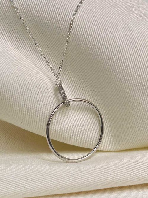 Gros plan collier posé sur un tissu blanc, le collier Lise en argent avec un pendentif en forme de cercle tenu par une baguette de zircon