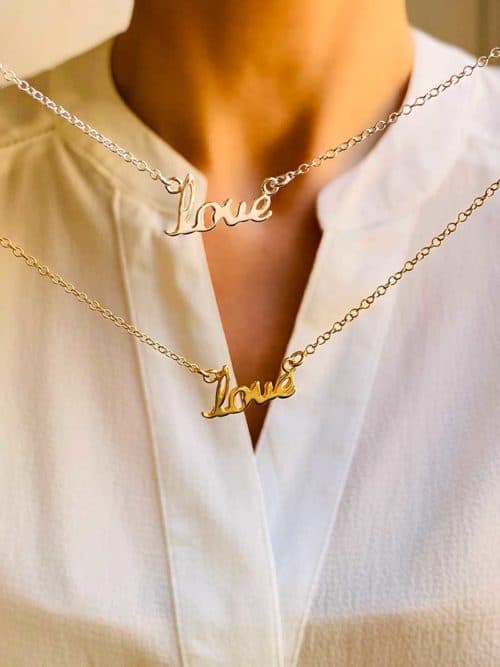 Vue de face cou flou avec 2 colliers un en argent et un en plaqué or. Le collier Love est composé d'une chaîne avec un love manuscrit