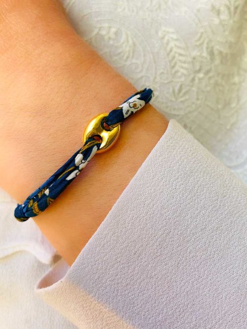 Vue de face gros plan poignet bracelet cordon liberty bleu avec pampille maille marine en plaqué or