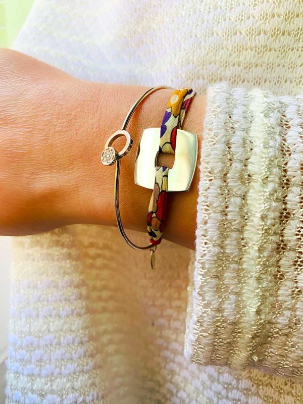 Vue de face gros plan poignet avec le bracelet cordon Charline avec un cordon impimé liberty et une plaque carrée en argent et le bracelet Laura un jonc en argent avec cercle en zircon