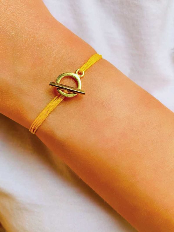 Vue de face gros plan poignet avec le bracelet cordon Zoé Doré avec une attache avec une barre dans un cercle en plaqué or