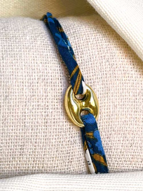Gros plan sur un tissu blanc un bracelet cordon imprimé liberty avec maille marine en plaqué or