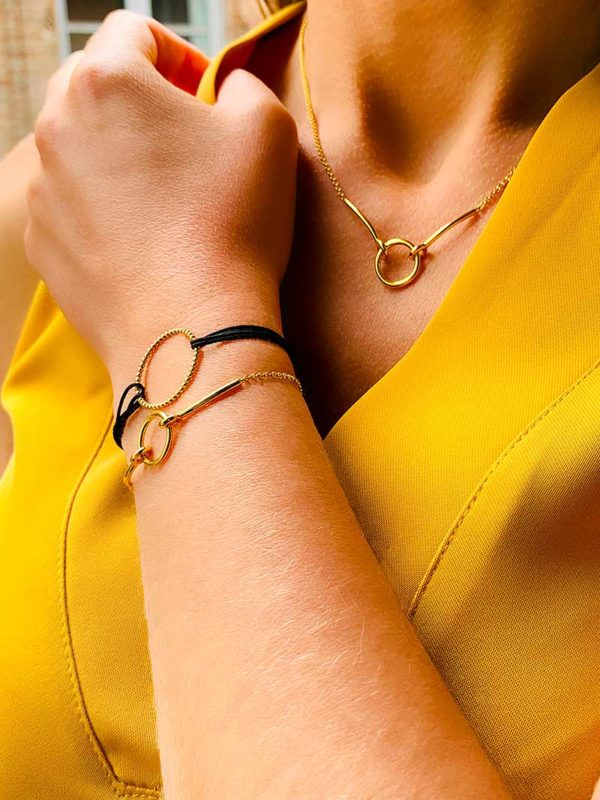 Vue de profil buste avec un bras relevé avec le bracelet Théa et le bracelet cordon Emma doré. Le collier Mya autour du cou. L'ensemble des bijoux sont en plaqué or 925/1000
