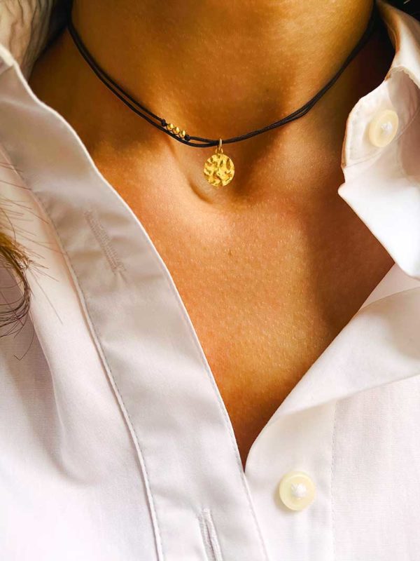Gros plan cou avec le collier cordon Romy Doré avec une plaque ronde martelée en plaqué or