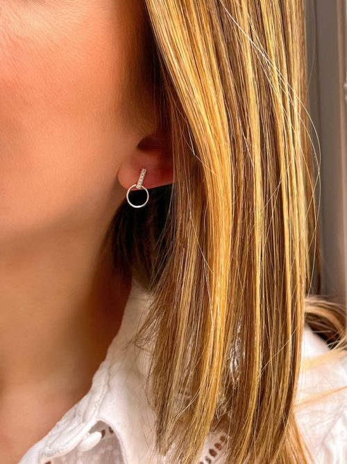 Gros plan Tête de femme de profil avec des boucles d'oreilles en argent avec un cercle ajouré relié par une baguette de zircons