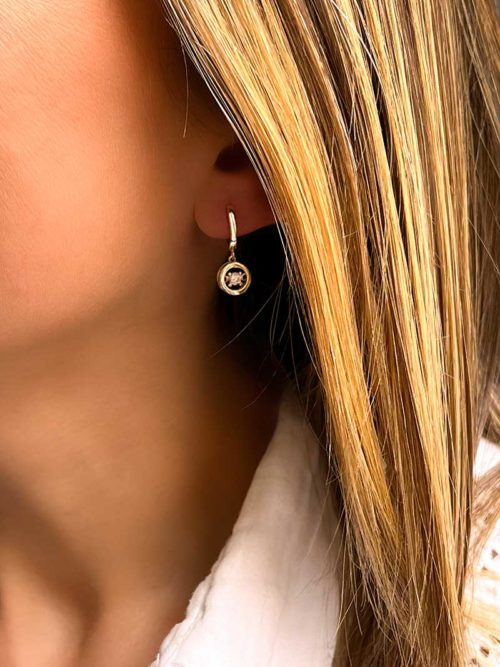 Gros plan Tête de femme de profil avec des boucles d'oreilles en plaqué or avec un cercle ajouré avec un gros zircon à l'intérieur