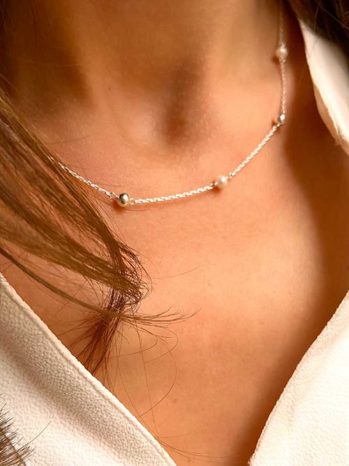 Gros plan cou de femme avec un collier chaîne avec des perles et des perles en argent