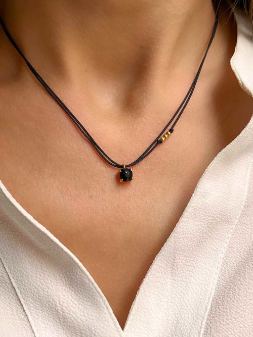 Gros plan buste de femme avec autour du cou le collier cordon Léa Doré avec une pierre semi précieuse d'agate noire de forme carrée cerclée de plaqué or