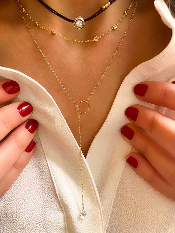 Gros plan cou de femme avec le collier cordon Joan Doré avec un zircon cerclé de plaqué or, le collier Elise Doré est un sautoir avec un zircon pendant dans un cercle, et le collier Emilie Doré avec une chaîne avec des petites pastilles martelées. bijoux fantaisies en plaqué or