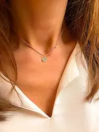 Gros plan cou de femme avec un collier cordon avec une plaque ronde avec un zircon. bijoux fantaisies en argent