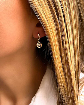 Gros plan visage femme avec boucles d'oreilles en argent avec un cercle ajouré avec un gros zircon à l'intérieur
