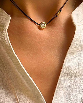 Gros plan cou de femme avec un collier cordon avec un zircon cerclé de plaqué or. bijoux fantaisies en plaqué or