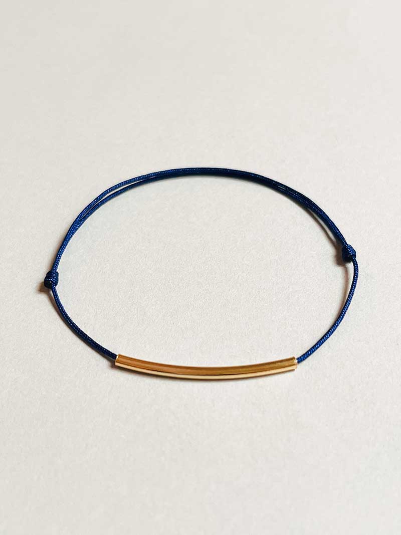 Gros plan bracelet cordon tube incurvé plaqué or