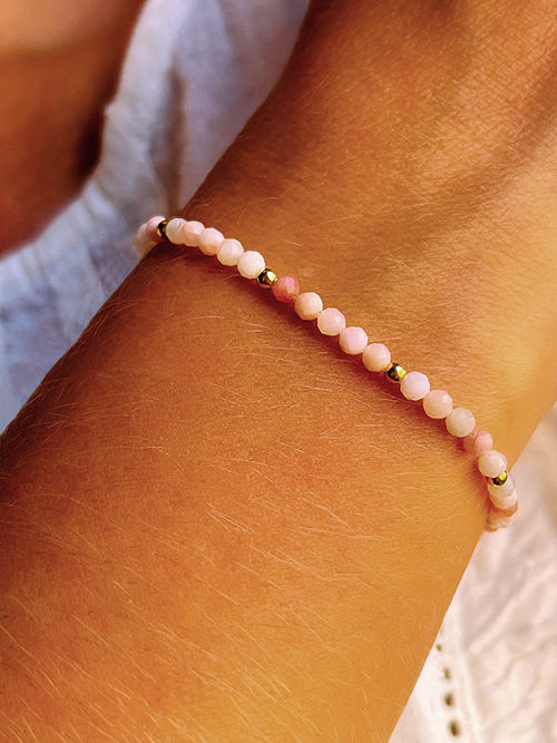 Gros plan bracelet élastique perles pierres naturelles opale rose plaqué or