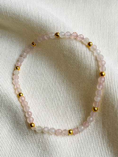 Gros plan bracelet élastique perles pierres naturelles quartz rose plaqué or