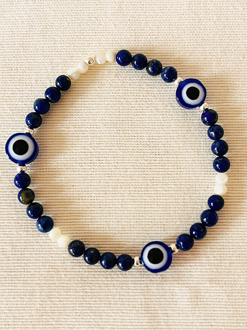 Gros plan bracelet élastique pierre naturelle lapis-lazuli nacre perles argent oeil bleu porte-bonheur