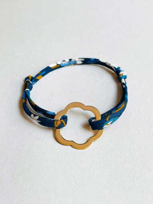 Gros plan sur un fond blanc le bracelet cordon Jade Doré avec un cordon imprimé liberty et une fleur ajourée en plaqué or