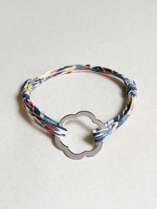 Gros plan sur un fond blanc le bracelet cordon Jade avec un cordon imprimé liberty et une fleur ajourée en argent