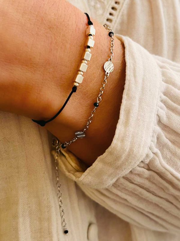 Gros plan bracelets cordon argent plaque pierre perle cube