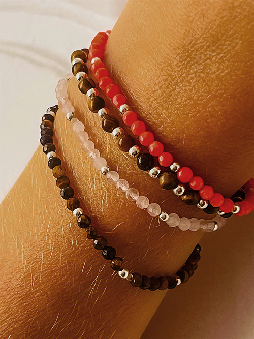 Gros plan bracelets pierres naturelles perles Oeil de Tigre Bambou de mer quartz rose plaqué or
