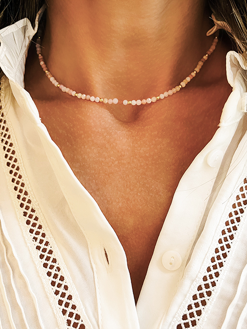 Gros plan collier élastique perles pierres naturelles opale rose plaqué or