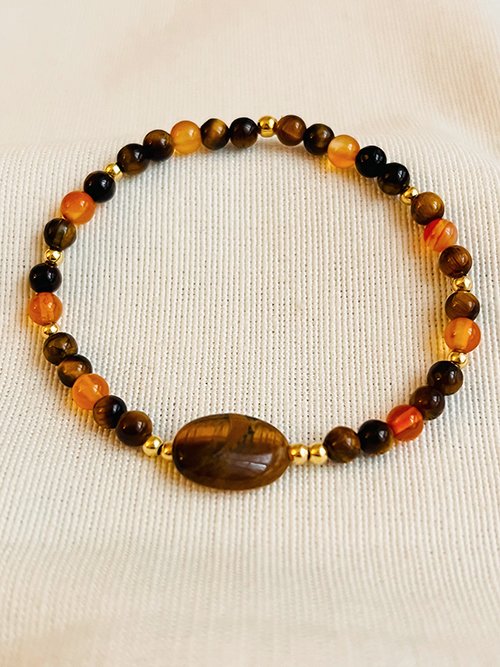 Gros plan bracelet élastique perles pierres naturelles oeil de tigre et cornaline et plaqué or