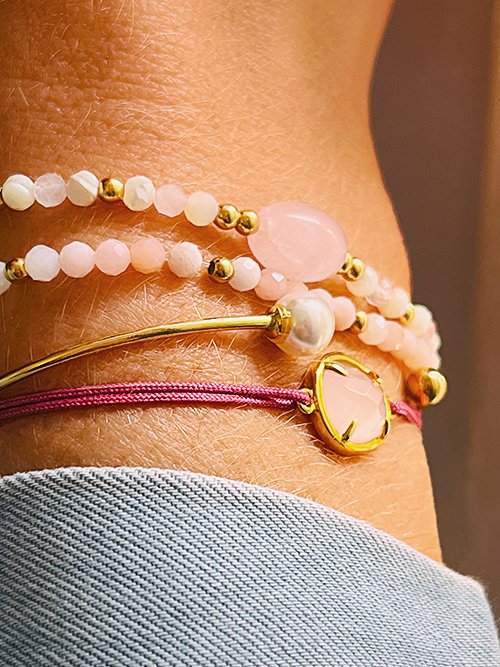Très gros plan bracelet élastique perles pierres naturelles quartz rose et nacre blanche et plaqué or jonc perle