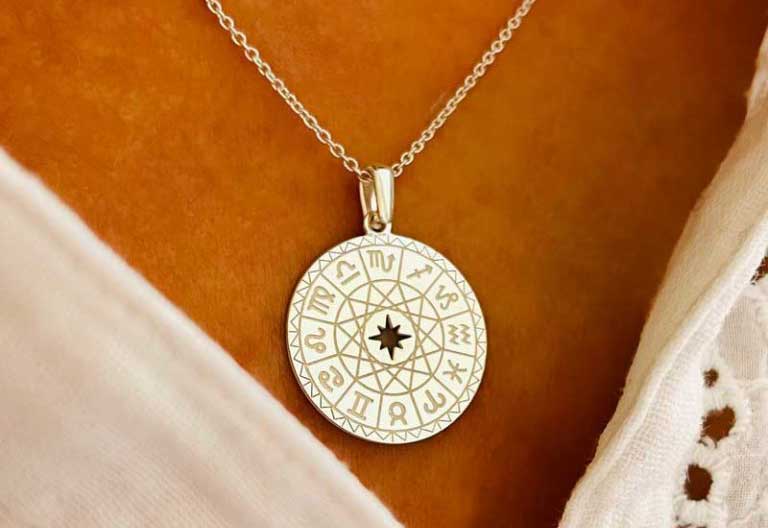 Gros plan collier pendentif plaque astral argent zodiaque